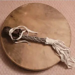 A wooden drum with a stick and string attached to it.
