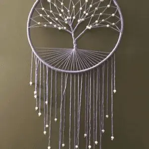 A white tree of life dreamcatcher hanging on the wall.